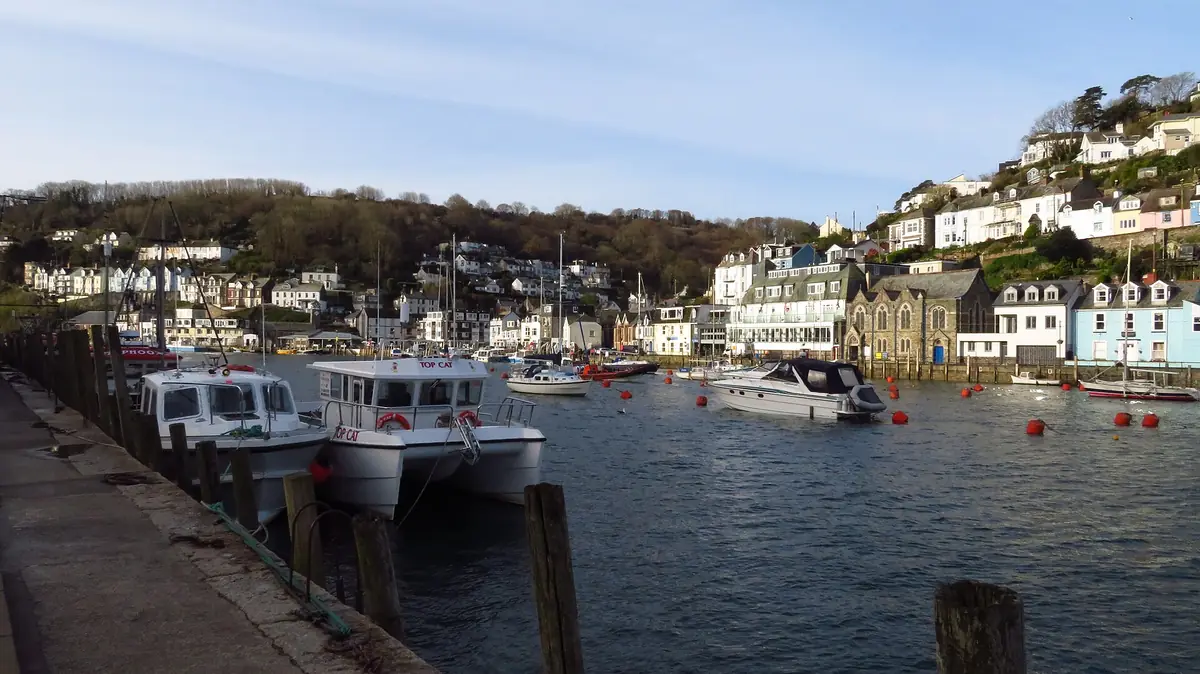 Boats moored in Looe harbour with West Looe on the hill