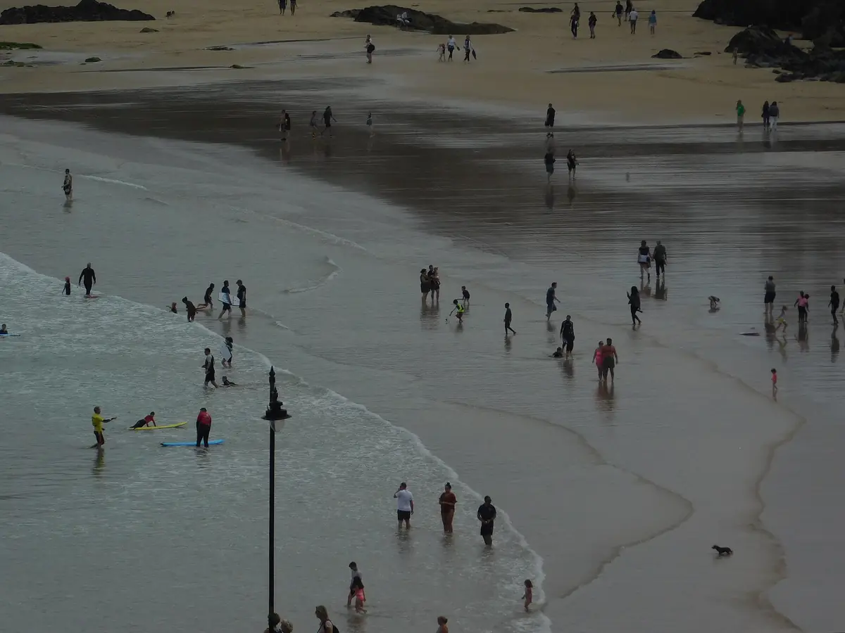 People on the sand at Newquay harbour beach at low tide