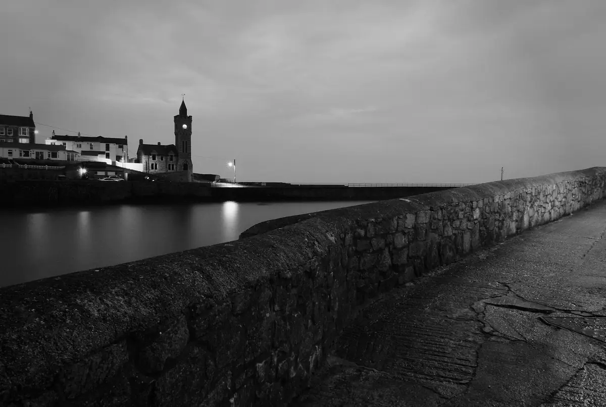Porthleven harbour wall and clock tower at dusk